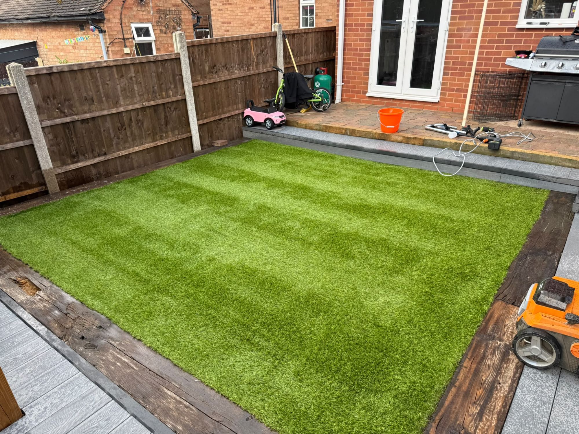 The finished artificial lawn alongside the patio, cleaned and brushed to a fresh finish