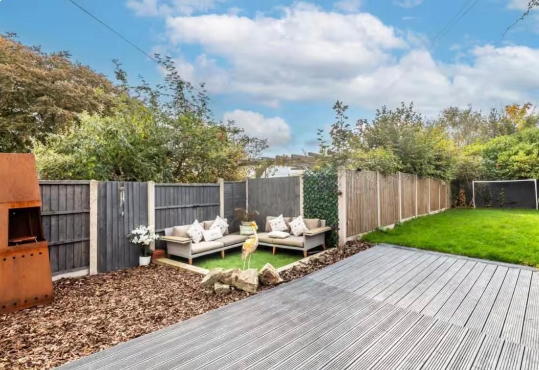 The same garden tidied, with a cut lawn, clean decking and a neat seating area