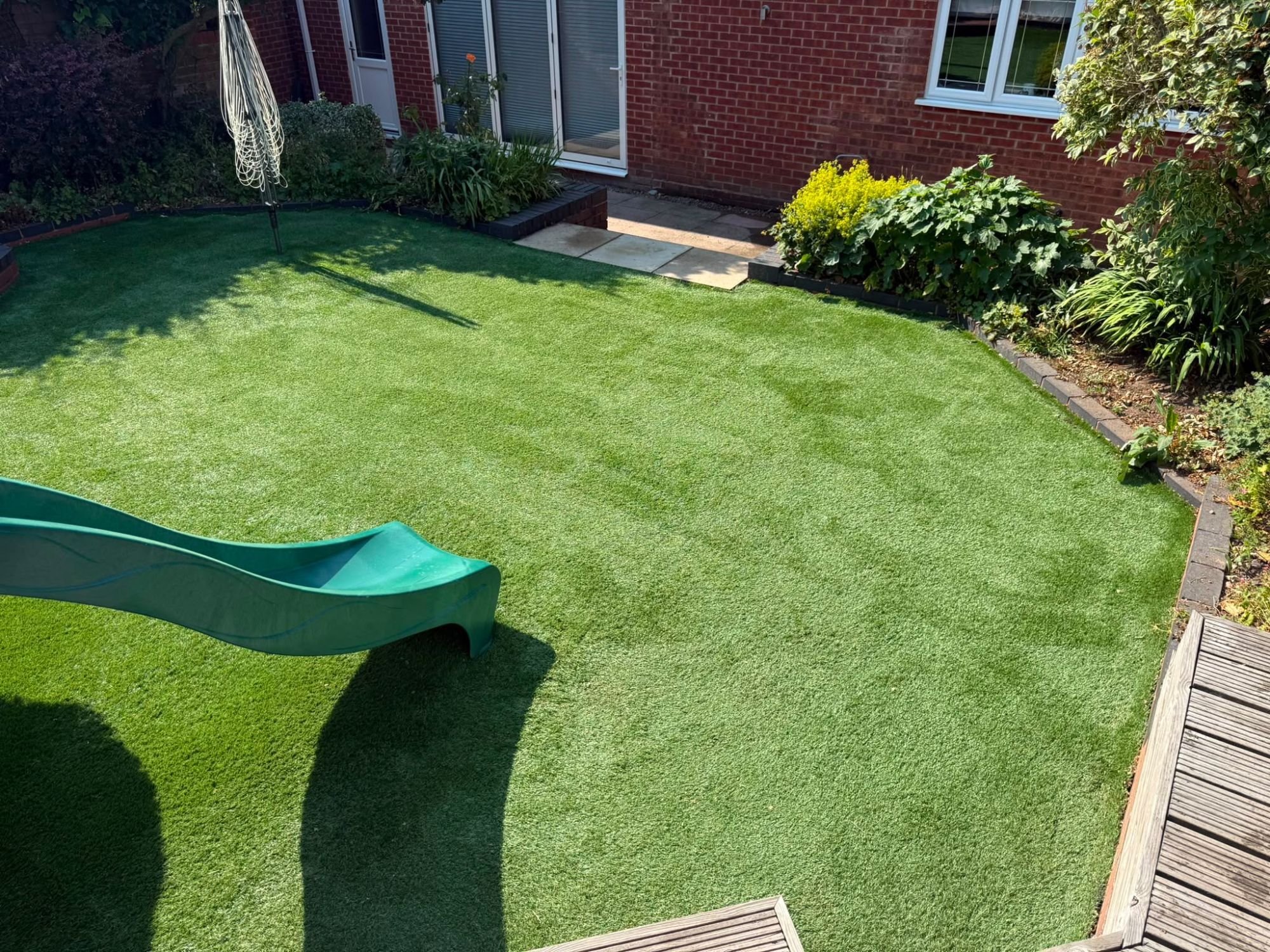 The same artificial lawn cleaned and brushed, clear of debris with the pile lifted and colour restored