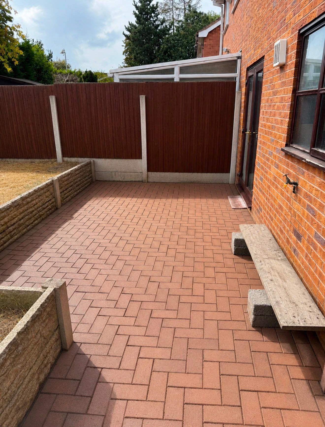 Block paving overgrown with weeds and moss pushing up through the joints