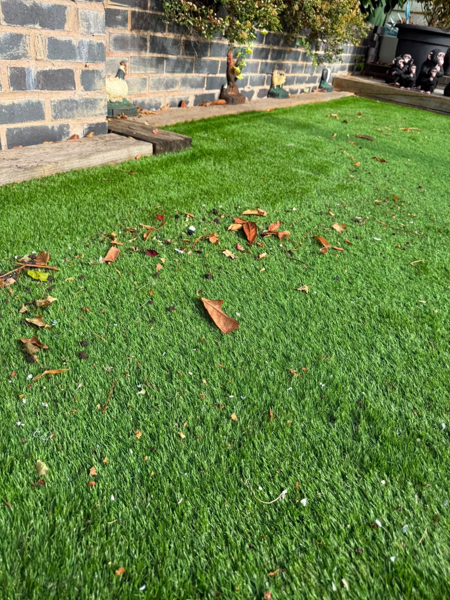 Artificial lawn scattered with fallen leaves and garden debris