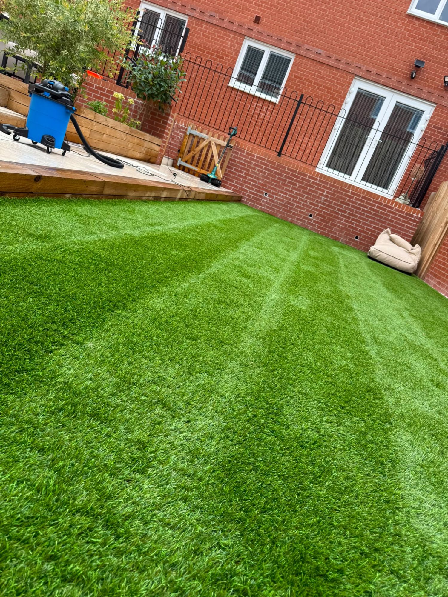 The same artificial lawn cleaned and brushed to a fresh striped finish